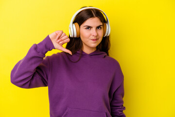 Young caucasian woman listening to music with headphones isolated on pink background showing a...