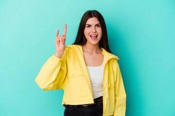 Young caucasian woman isolated on blue background showing rock gesture with fingers