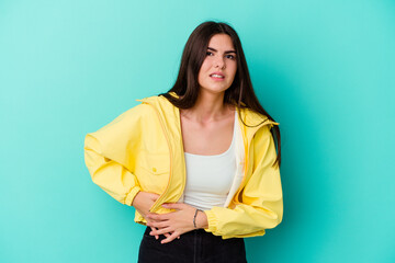 Young caucasian woman isolated on blue background having a liver pain, stomach ache.