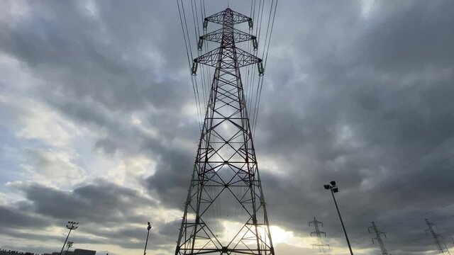 High voltage power lines tower with branching wires - Moving towards and underneath it with sunset on the background