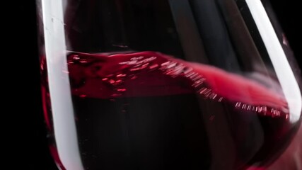 Wine mixing inside goblet. Whirling red wine in wine glass at dark background. Pouring red wine into goblet. Close-up shot of wineglass