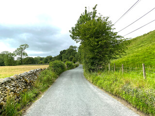Looking along, Hazler Lane, with dry stone walls, corn fields, old trees, and a cloudy sky near, Appletreewick, Skipton, UK