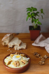 Typical Manchego dish made with cod on a wooden table with slices of bread and walnuts