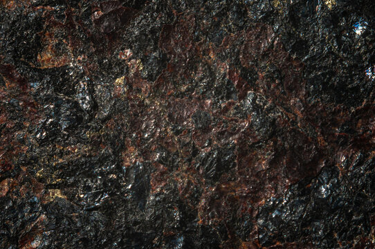 Textured surface of dark natural stone with various inclusions. Abstract background.