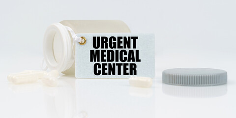 Fototapeta na wymiar On a white reflective background, there are pills and a jar of drugs with a tag that says - URGENT MEDICAL CENTER