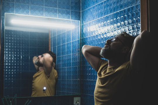 Close Up Of One Sad Depressed Man Looking Himself In The Mirror Of The Bathroom Reflexing About His Life Or Lifestyle. Sick Male Person Unhappy Thoughtful..