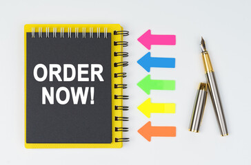 On a white background lies a pen, arrows and a notebook with the inscription - ORDER NOW