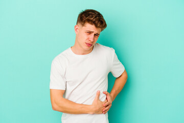 Young caucasian man isolated on blue background having a liver pain, stomach ache.
