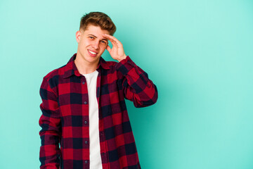 Young caucasian man isolated on blue background shouts loud, keeps eyes opened and hands tense.