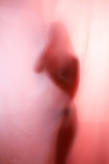 Silhouette of girl behind a curtain. Blurry hand and body figure abstract.