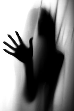 Silhouette of girl behind a curtain. Blurry hand and body figure abstract. Black and white picture