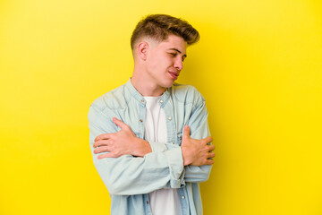 Young caucasian man isolated on yellow background hugs, smiling carefree and happy.