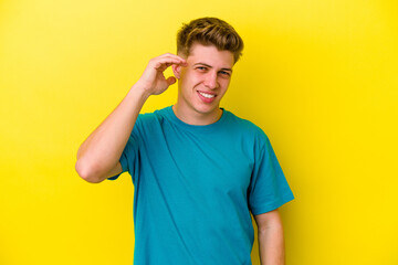 Young caucasian man isolated on yellow background laughing about something, covering mouth with hands.