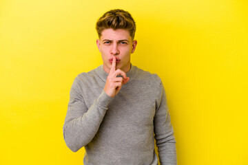 Young caucasian man isolated on yellow background keeping a secret or asking for silence.