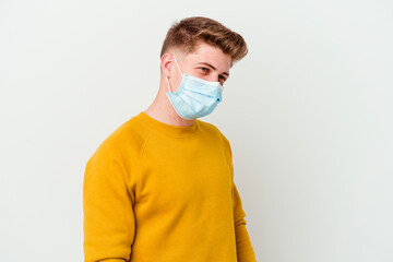 Young man wearing a mask for coronavirus isolated on white background looks aside smiling, cheerful and pleasant.