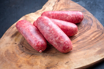 Traditional Italian raw salsiccia fresco meat sausage offered as close-up on a rustic wooden cutting board
