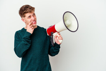 Young caucasian man holding a megaphone isolated on white background relaxed thinking about something looking at a copy space.