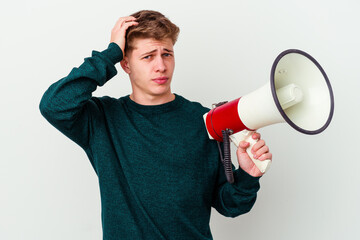 Young caucasian man holding a megaphone isolated on white background being shocked, she has remembered important meeting.
