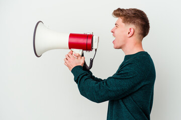 Young caucasian man holding a megaphone isolated on white background shouting and holding palm near opened mouth.