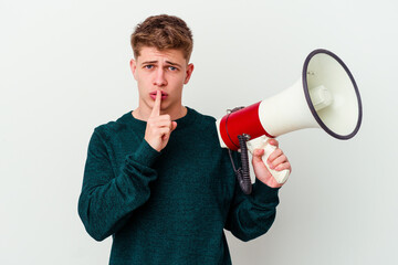 Young caucasian man holding a megaphone isolated on white background keeping a secret or asking for silence.