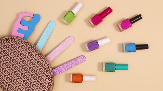Manicure set and tools appear from manicure kit on beige background. Stop motion flay lay