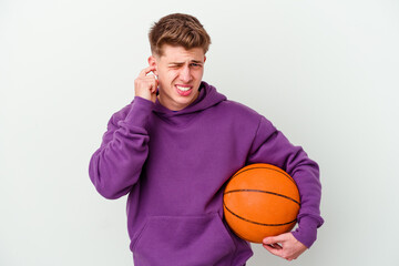 Obraz premium Young caucasian man playing basketball isolated background covering ears with hands.