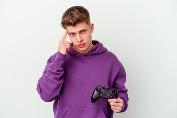 Young caucasian man holding a gamepad isolated on white background pointing temple with finger, thinking, focused on a task.