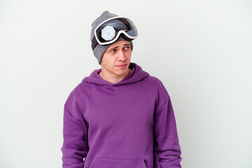 Young man holding a snowboard board isolated on white background confused, feels doubtful and unsure.