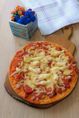 Appetizing hot homemade pizza from yeast dough, ready to eat on a wooden board.