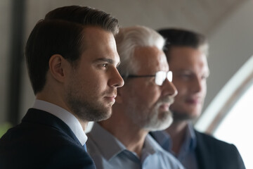Close up of diverse male employees colleagues look in distance think of future career opportunities. Pensive businessmen plan or visualize in office workplace. Business vision, leadership concept.