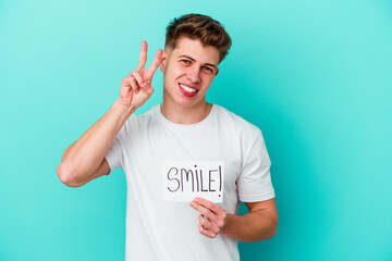 Young caucasian man holding a smile placard isolated on blue background