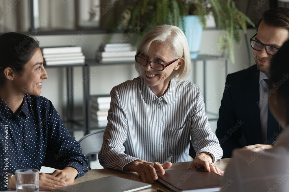 Canvas Prints smiling multiethnic businesspeople gather at desk in office talk discuss business ideas together. ha