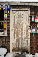 Weather beaten and worn doorway of a lobsterman's fishing shack with colorful buoys
