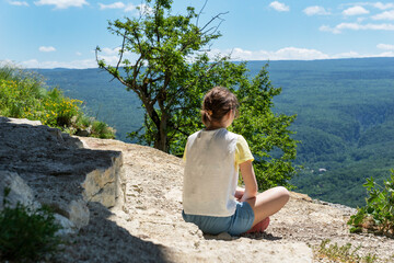 Young female sit on rock and near tree on high mountain peak Feeling of freedom, relaxation while looking at scenery mountain scenes.