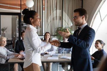Confident Caucasian male boss or director greet congratulate excited African American female...