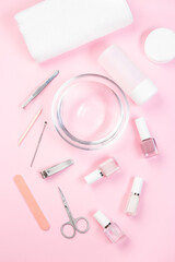 Spa set, manicure or pedicure equipment with nail coat or polish, on pink background, vertical, top view