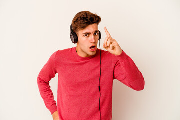 Young caucasian man listening to music isolated on white background having an idea, inspiration concept.