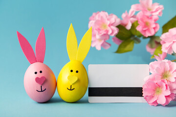 Shopping online. Ordering Easter. Easter eggs, bunny, credit card on blue background. Online store.
