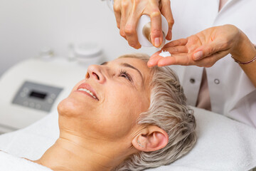 Beautiful senior woman getting spa massage treatment at beauty spa salon. Facial beauty treatment.