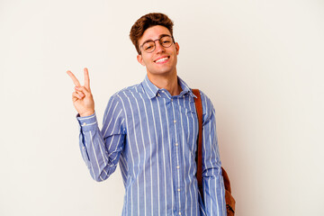 Young student man isolated on white background joyful and carefree showing a peace symbol with fingers.