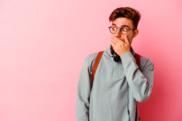 Young student man isolated on pink background thoughtful looking to a copy space covering mouth with hand.