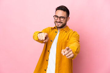 Young caucasian handsome man isolated on pink background pointing front with happy expression