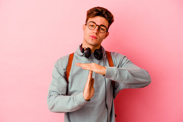Young student man isolated on pink background showing a timeout gesture.