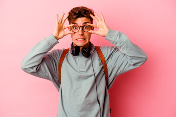 Young student man isolated on pink background keeping eyes opened to find a success opportunity.