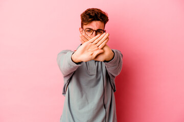 Young student man isolated on pink background doing a denial gesture