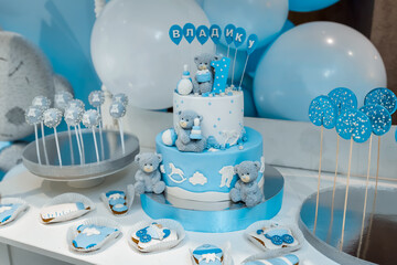 Baby birthday theme with teddy bear. Festive background decoration with cake, letters saying one and white blue balloons in studio, Candy bar.