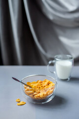Morning healthy breakfast variety concept. glass bowl of milk next to cornflakes in a glass on a grey background. Top view. Healthy eating.