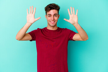 Young caucasian man isolated on blue background showing number ten with hands.