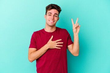 Young caucasian man isolated on blue background taking an oath, putting hand on chest.