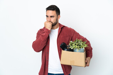 Young caucasian man making a move while picking up a box full of things isolated on white...